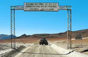 Portal fronterizo "Aduana Nacional de Bolivia – Apacheta Hito Cajones" con un vehículo 4x4 cruzando en paisaje desértico.