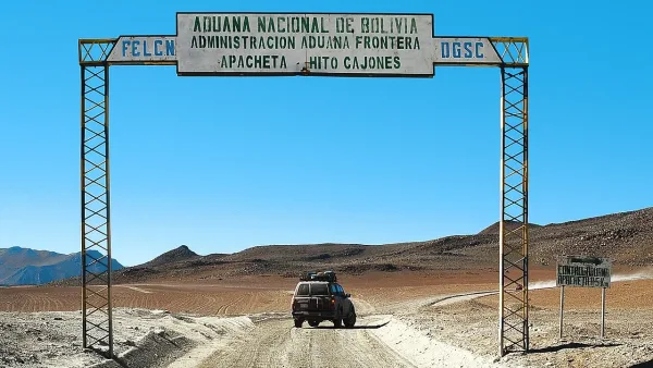 Portal da Aduana Nacional de Bolivia em Apacheta - Hito Cajones, com um veículo 4x4 passando pela fronteira desértica.