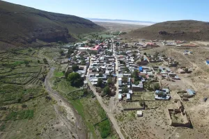 Vista aérea del poblado de Colcha K, rodeado de cerros áridos, cultivos en terrazas y un salar al fondo.