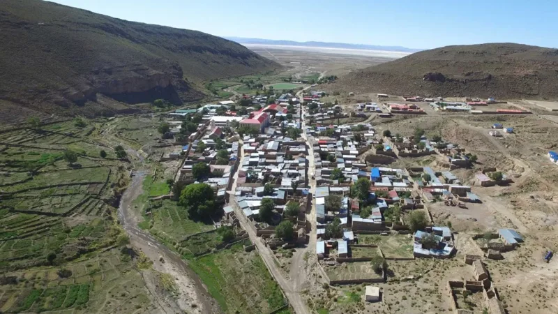 Vista aérea del poblado de Colcha K, rodeado de cerros áridos, cultivos en terrazas y un salar al fondo.