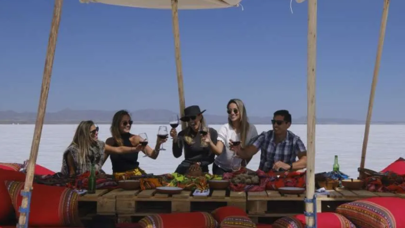 Grupo de pessoas brinda com vinho durante almoço ao ar livre no Salar de Uyuni, Bolívia